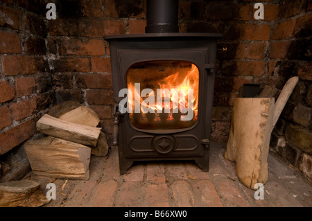 A small energy efficient cast iron wood burning stove with logs, UK Stock Photo