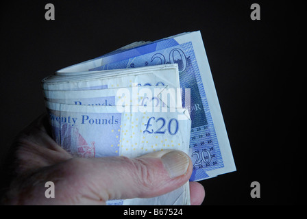 Handful of English £20 notes held in a roll Stock Photo