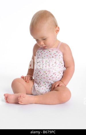 Sitting baby girl looking at her own feet Stock Photo