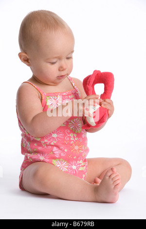 Sitting baby girl with a toy Stock Photo