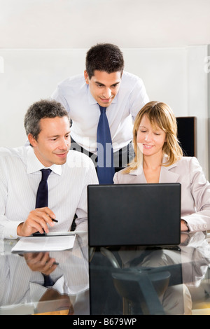 Businesspeople looking at laptop in meeting room Stock Photo