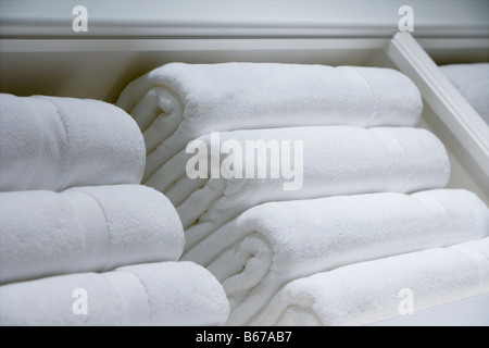 Stacks of fresh white towels on a shelf. Stock Photo