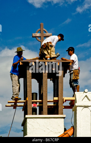 Hispanic workmen prepare to replace roof covering of the bell tower of a Catholic church in Laguna Beach CA Stock Photo