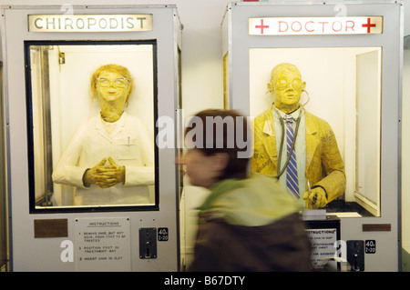 A woman walks past the 'Doctor' and 'Chiropodist' machines in the amusement arcade, Southwold pier, Suffolk, England Stock Photo