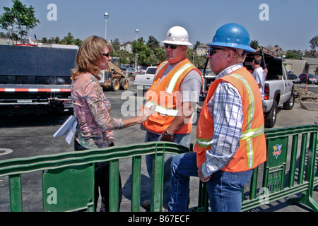 A woman construction supervisor briefs two workmen at a shopping mall job site in Laguna Niguel CA Note hard hats and vests Stock Photo