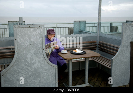 An elderly lady having coffee alone, The Pier, Southwold, Suffolk, England Stock Photo