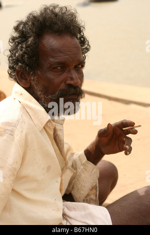 Boat man in India, resting and smoking a cigarette Stock Photo