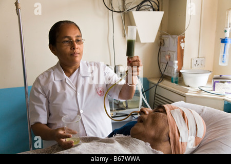 Nurse feeding a very sick patient though a tube in intensive care ward of the New Civil Hospital, Surat. Gujarat. India. (44) Stock Photo