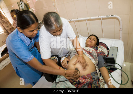 Maternity nurses examine heavily pregnant woman patient in the maternity ward of the New Civil Hospital, Surat. Gujarat. (44) Stock Photo