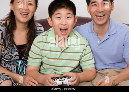 Mature couple sitting with their son playing video game Stock Photo