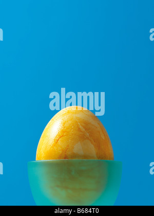 Yellow Easter Egg in Blue Eggcup Stock Photo