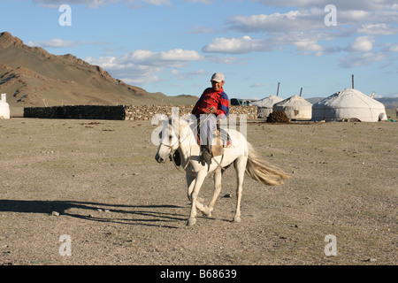 Mongolian boy racing on a horse in front of nomads tent Mongolia Stock Photo