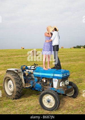 Couple kissing on top of tractor Stock Photo