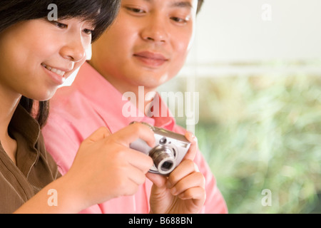 Young woman holding a digital camera with a young man beside her Stock Photo