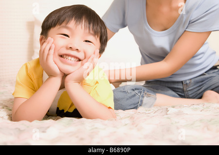 Close-up of a boy leaning on his elbows and her mother sitting near him Stock Photo