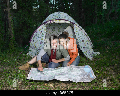 Couple reading map in front of tent Stock Photo