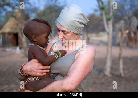 A woman cuddles a young Himba baby at the the Himba Oase Village, near Kamanjab, Namibia Stock Photo