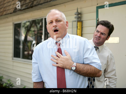 A mature businessman suffering from sudden chest pain A coworker looks worried Stock Photo