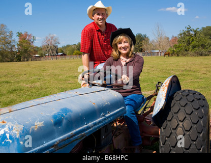 Beautiful mature couple riding a tractor on their farm Stock Photo