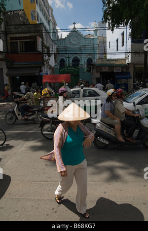 Vietnamese woman wearing a conical hat in busy Ho Chi Minh City, Vietnam