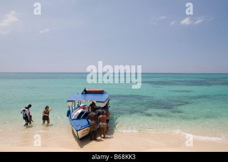 Jamaica Montego Bay Tourists walk toward glass bottomed boat along white sand beach Stock Photo