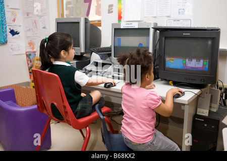 Two 4 year old preschool girls sitting at computers in school Stock Photo