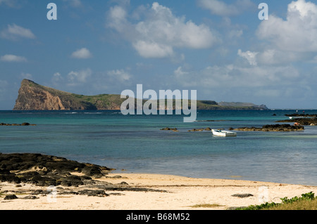 View of Coin de Mire island and the beach at Cap Malheureux with turquoise coral sea and white boat. Stock Photo