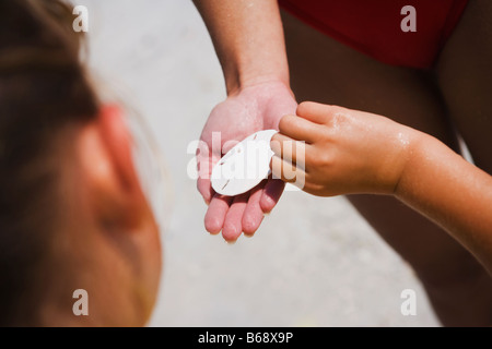 Woman giving girl disc-shaped object, close-up Stock Photo