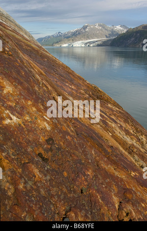 USA Alaska Glacier Bay National Park Rocky coast colored by iron oxide stains overlooking Lamplugh Glacier Stock Photo