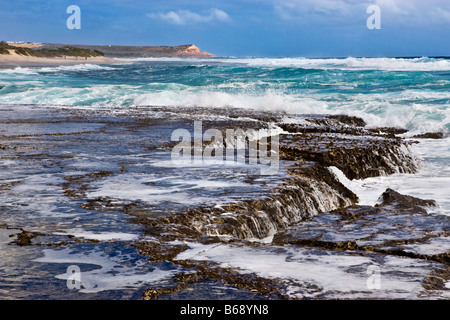 Waves breaking on the rocky coastline of Kalbarri National Park with Red Bluff in the distance, Western Australia Stock Photo