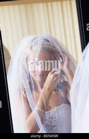 Bride in wedding dress looking at herself in mirror Stock Photo