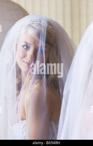 Bride wearing veil looking at herself in mirror Stock Photo