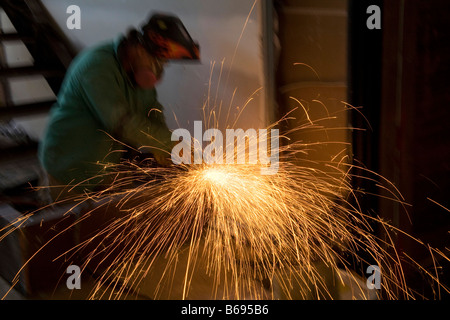 Welder in hat sparks flying working on staircase Stock Photo
