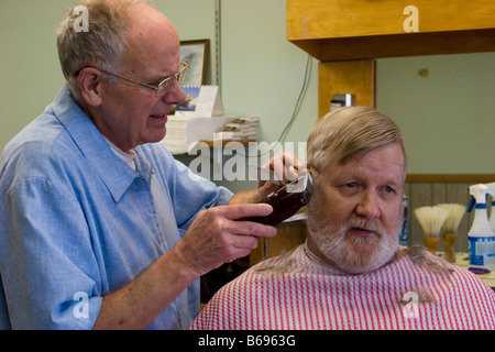Barber cutting a man's hair in barber shop Stock Photo