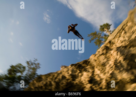 Jamaica Negril Young man leaps from cliff above Pirates Cave Stock Photo