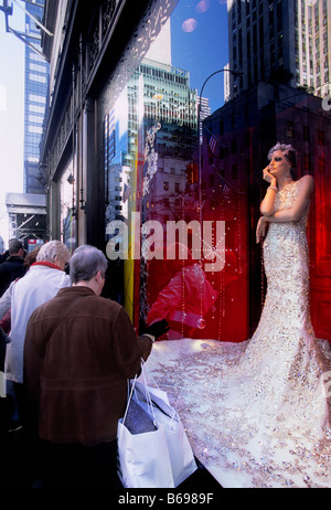 New York City, Saks Fifth Avenue. Tourists admiring dress in the storefront window display. USA Stock Photo