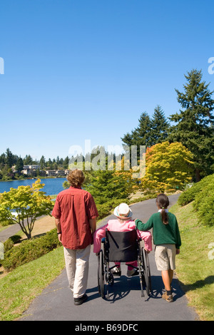 Man with a girl assisting a woman in a wheelchair Stock Photo