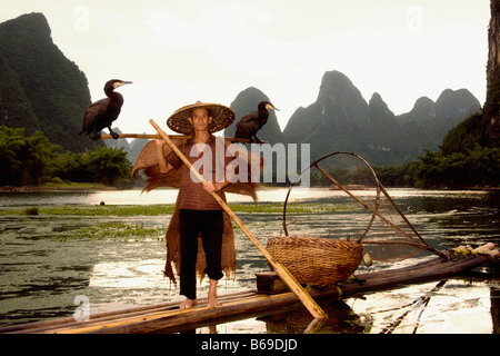 Senior man on a bamboo raft with a hill range in the background, Guilin Hills, XingPing, Yangshuo, Guangxi Province, China Stock Photo