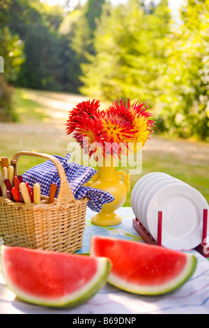 Two watermelon slices with a basket and a vase of flowers on a table Stock Photo