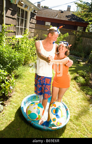 Couple wearing snorkels and dancing in a wading pool Stock Photo