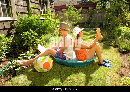 Couple reading books in a wading pool Stock Photo