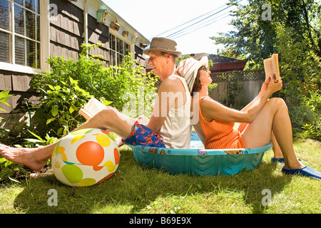 Couple reading books in a wading pool Stock Photo