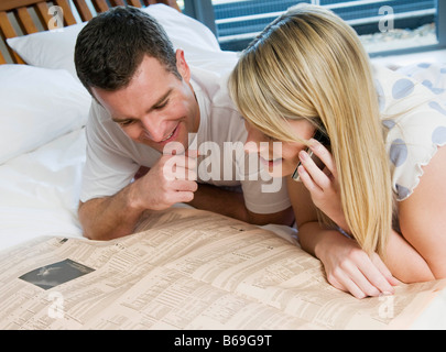 Couple check stocks and shares in bed Stock Photo