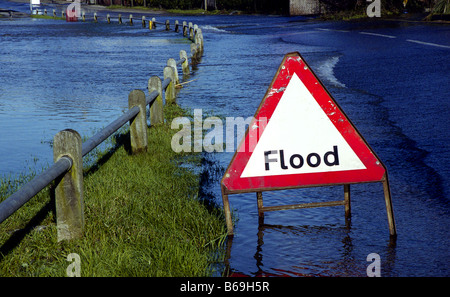 Flood warning sign with flooded road in background Stock Photo