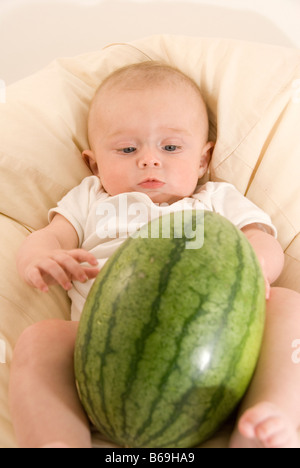 Baby Boy Sitting in White Cream Beanbag Playing with Big Green Watermelon Stock Photo