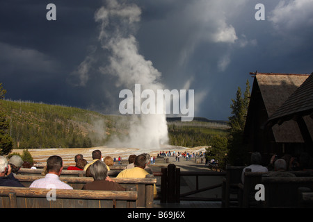 Watching Old Faithful erupt from the viewing deck of the Old Faithful Inn, Yellowstone National Park, Wyoming Stock Photo