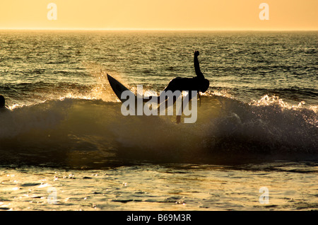 A surfer in action on a wave at sunset at Woolacombe Beach in Devon Stock Photo