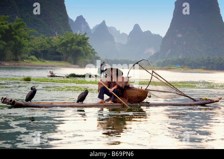 Fisherman fishing in a river with a hill range in the background, Guilin Hills, XingPing, Yangshuo, Guangxi Province, China Stock Photo