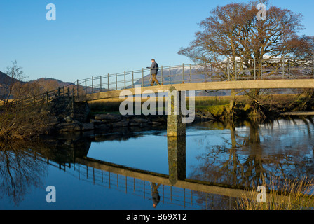 Man walking on footbridge over River Derwent, Borrowdale, Lake District National Park, Cumbria, England UK Stock Photo