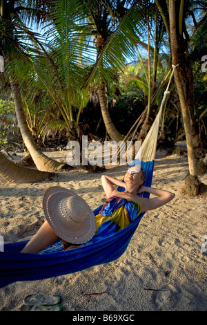 Mexico, Quintana Roo, Tulum, Tourist (woman) in hammock under palm trees at beach Stock Photo